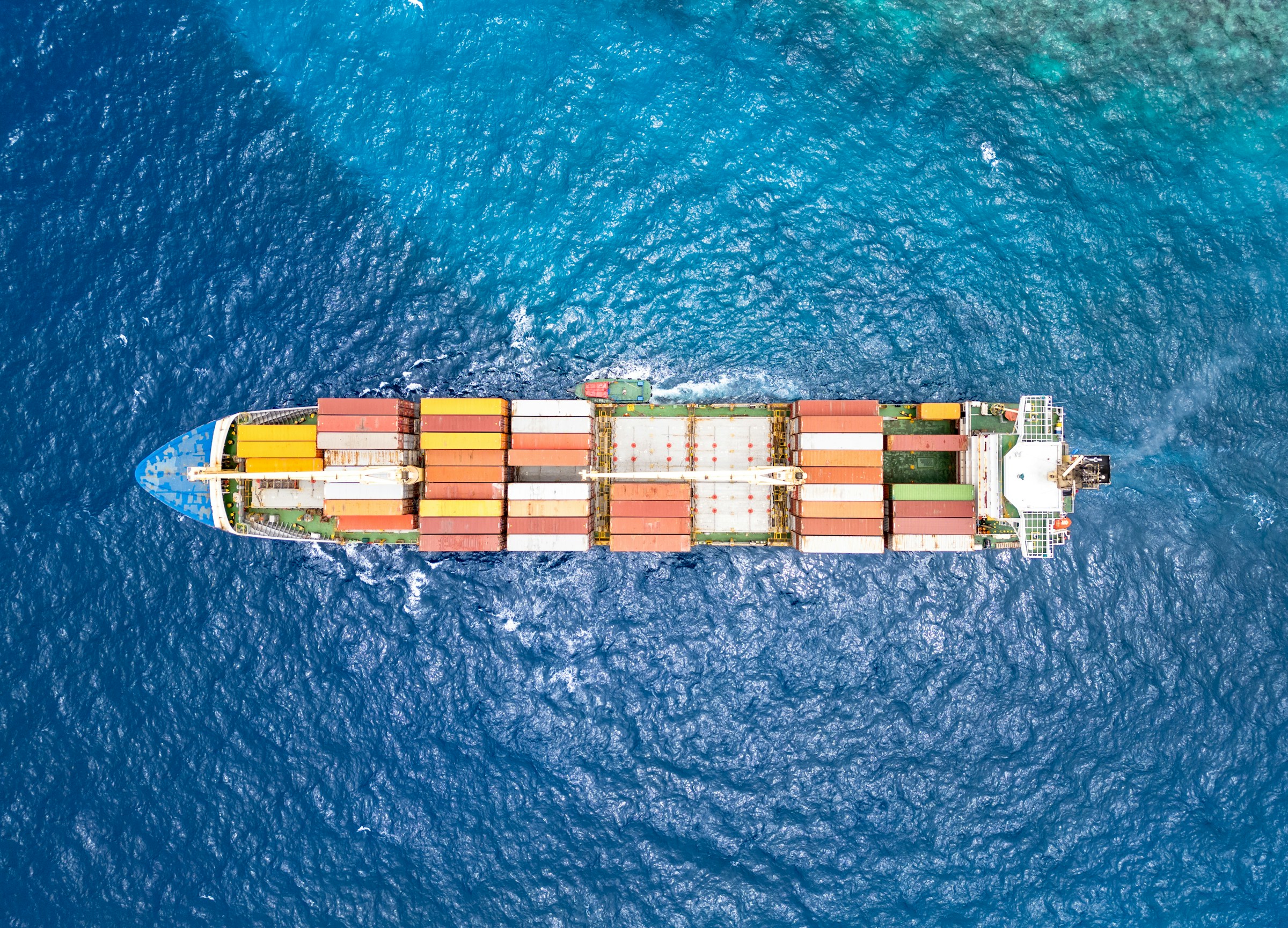 A container ship crossing the open sea, viewed from above